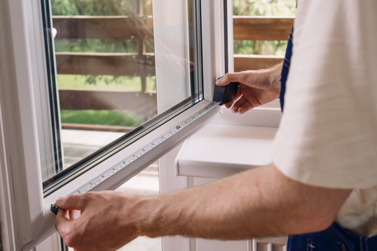 Handwerker montiert Insektenschutz an einem Fenster